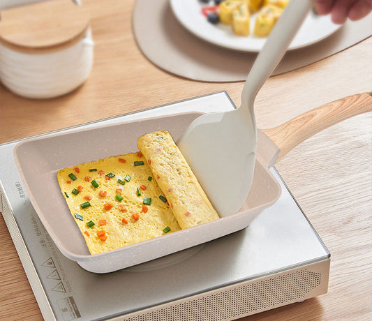 Non-stick frying pan with omelette and spatula on a wooden table
