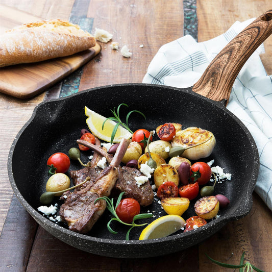 Skillet with lamb chops and vegetables on a wooden table